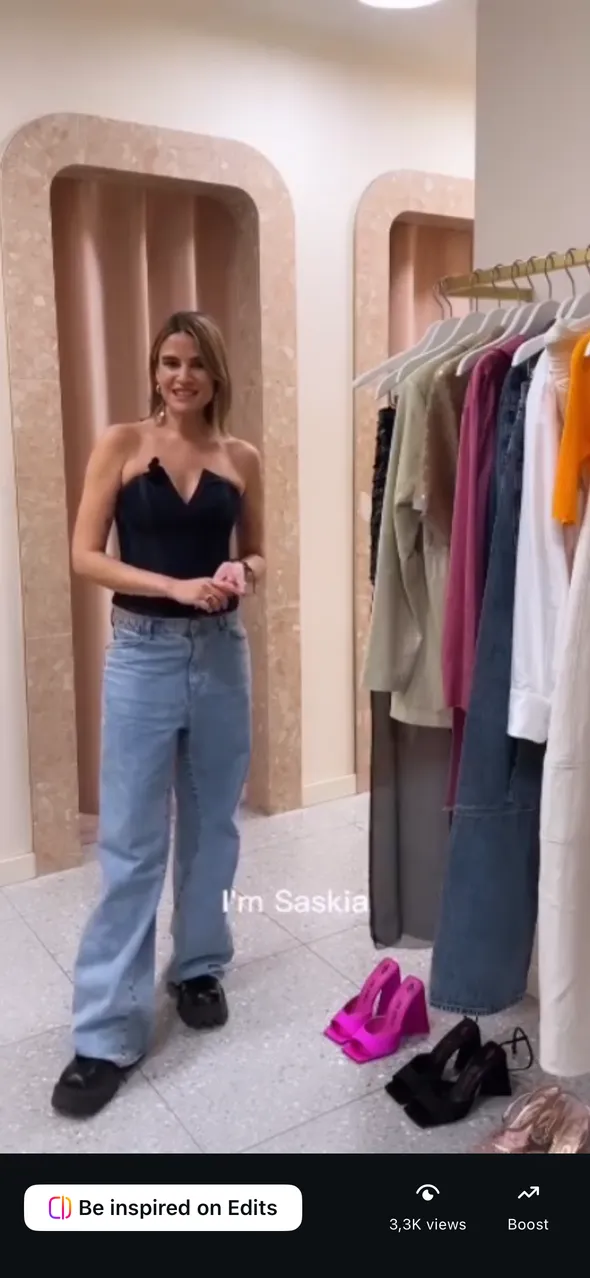 Saskia Jung presenting beside a rail of garments in a KaDeWe fitting space.